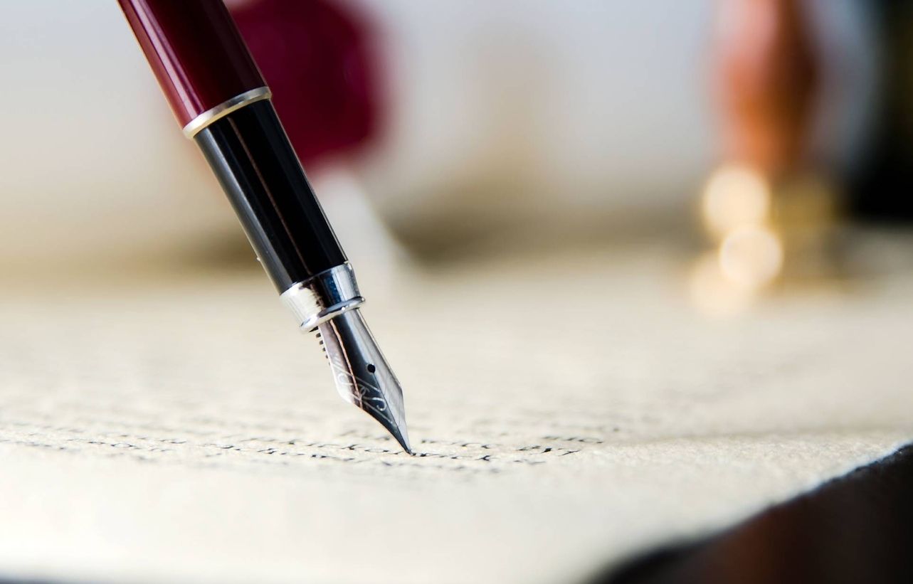 Ein Füller in rot schreibt auf altem Papier