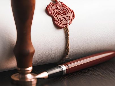 Ein Füller, eine Siegelstempel und eine Pergamentrolle auf einem Tisch