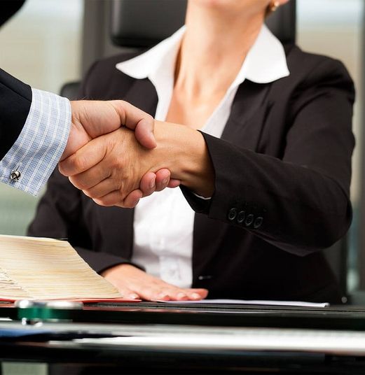 Eine Frau in Hemd und Blazer gibt einem Mann die Hand